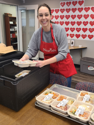 A Nourish volunteer packs prepared meals into an insulated carrier.