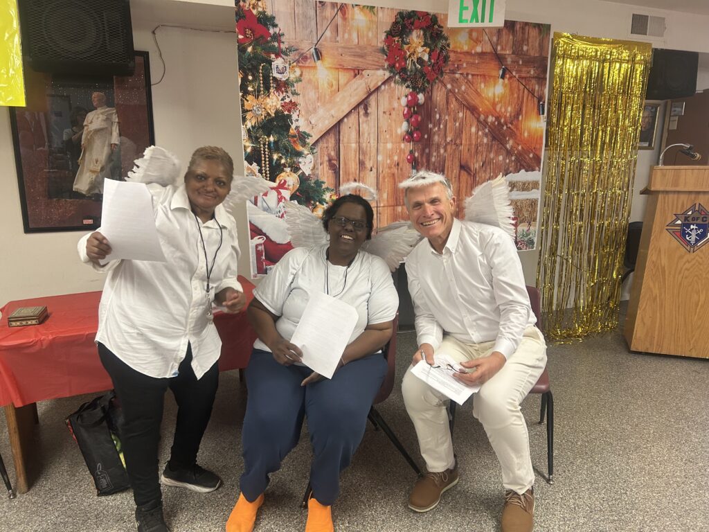 Three people smiling together at a Little Flower volunteer gathering.