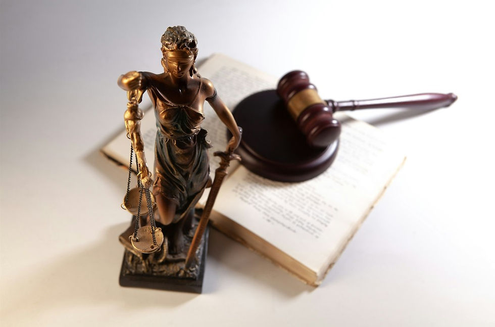 Lady Justice statue with scales beside a gavel resting on an open book, symbolizing law and justice on a white background