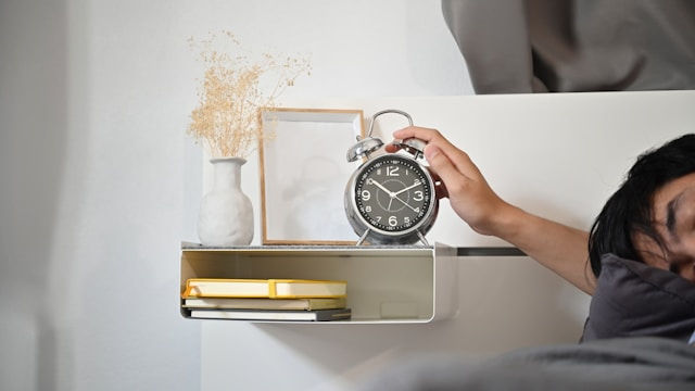 a man sleeping and turning off the alarm