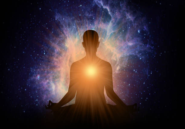 Silhouetted person meditating with glowing chest center against a colorful cosmic nebula, serene and spiritual