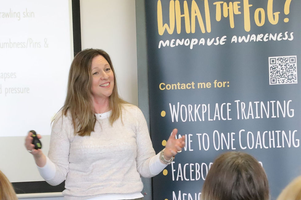 Woman giving a presentation on menopause awareness. Banner reads "WHAT the FoG? Menopause Awareness" with services listed. She is smiling.