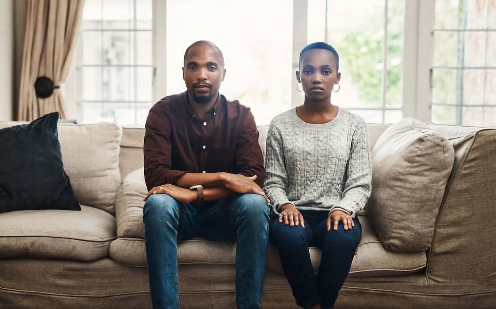 shot of a young couple looking serious and sitting alongside each other on a sofa at home