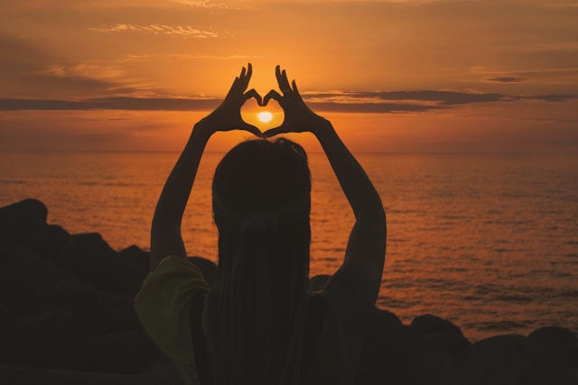 Silhouette of a woman doing a heart sign.