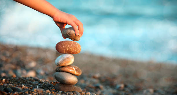 close up shot of child hand playing with stones on beach