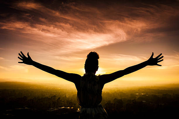 American Woman Raising Arms at Sunset