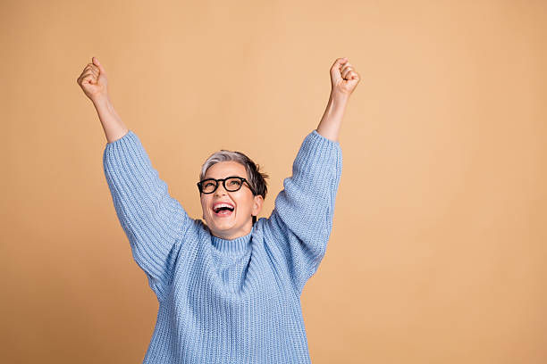 Woman in a pink sweater holds a teal awareness ribbon in cupped hands against a soft green background, conveying a message of support.