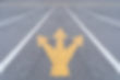 Yellow three-way arrow on a gray asphalt road, with multiple lanes marked by white lines, symbolizing direction choice. Overcast mood.