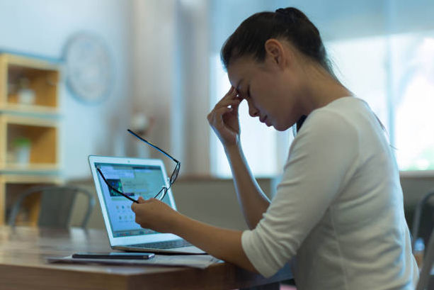 Exhausted and stressed out woman taking a break from the computer, rubbing her sore eyes.