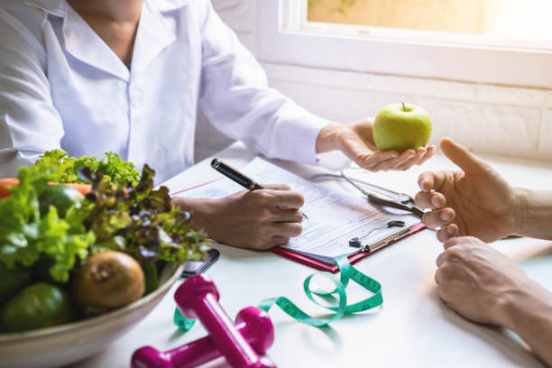 A nutritionist giving a consultation to a patient with healthy fruits and vegetables.