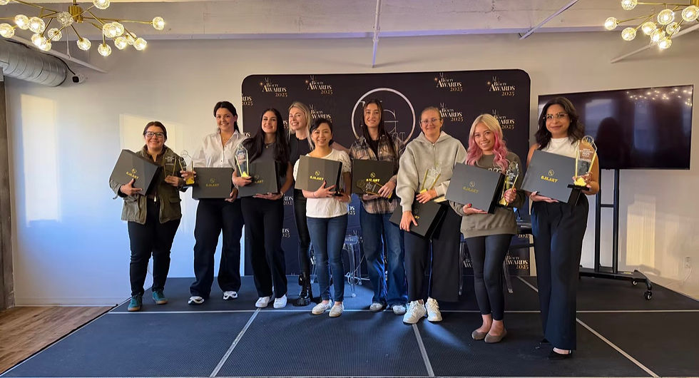Nine women smiling and holding awards and G.MART boxes on a stage at a ceremony. Background has "Beauty Awards 2025" signage.