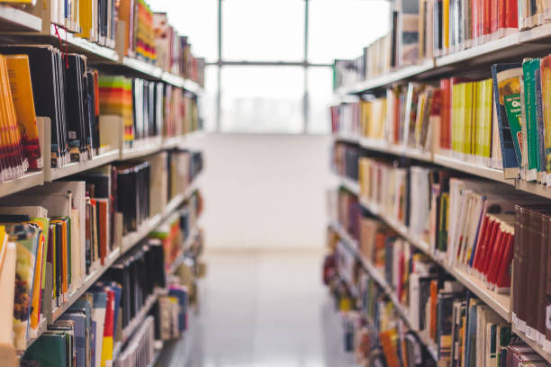 Library aisle lined with colorful books on both sides, leading to a bright window in the background.