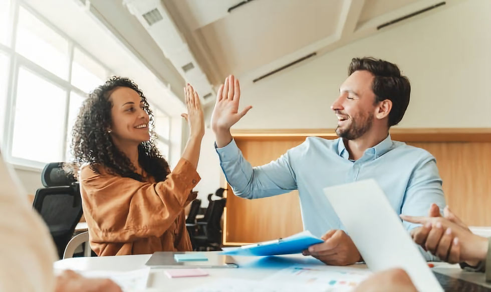 Man and woman giving high five to each other sitting in modern office