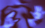 Abstract image of a blurred figure with hands raised, backlit by blue and purple hues, creating a mysterious, ethereal atmosphere.