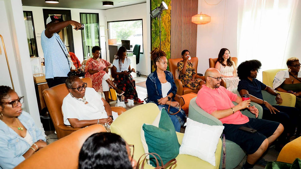 Diverse adults sit in a bright modern lounge while one man takes a photo, creating a relaxed workshop atmosphere.