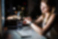 A woman sits at her desk at night, looking at her smartwatch.