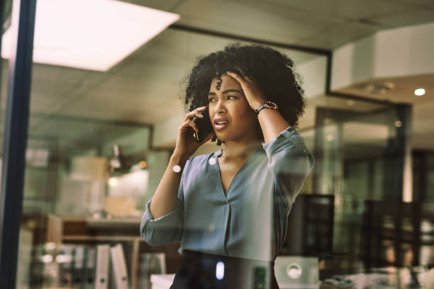 Businesswoman looking stressed while using a smartphone during a late night at work