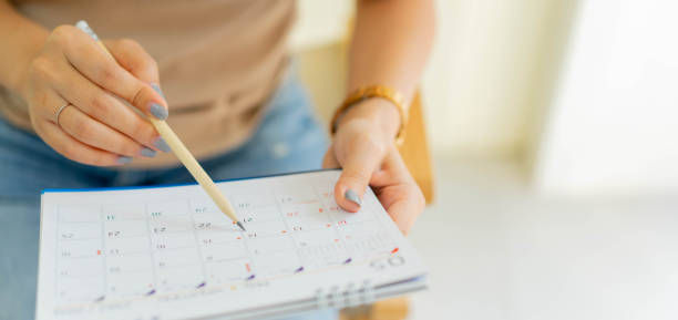 woman hand using pen to writing schedule on calendar