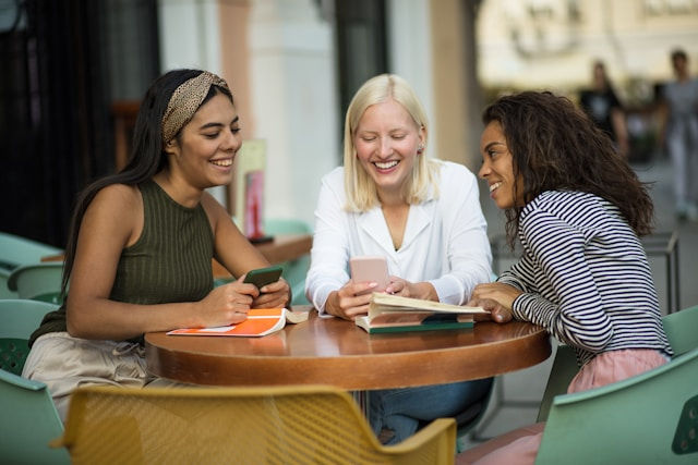 Three women are sitting outside the cafe.