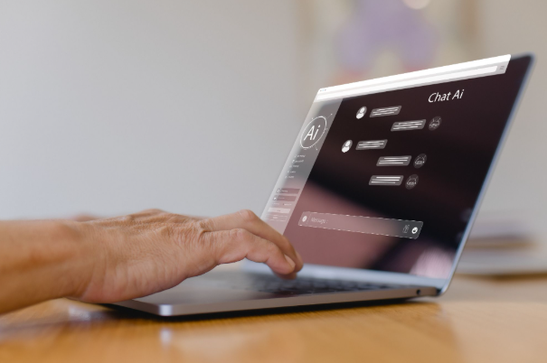 Hand using a laptop on a wooden desk, with a dark Chat AI interface on screen.