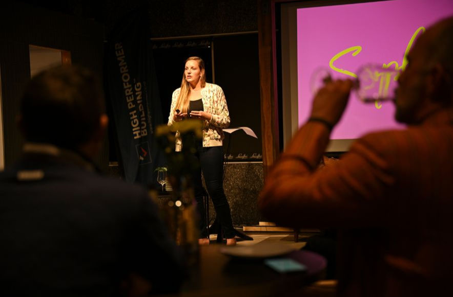 a woman speaking in the stage infront of people