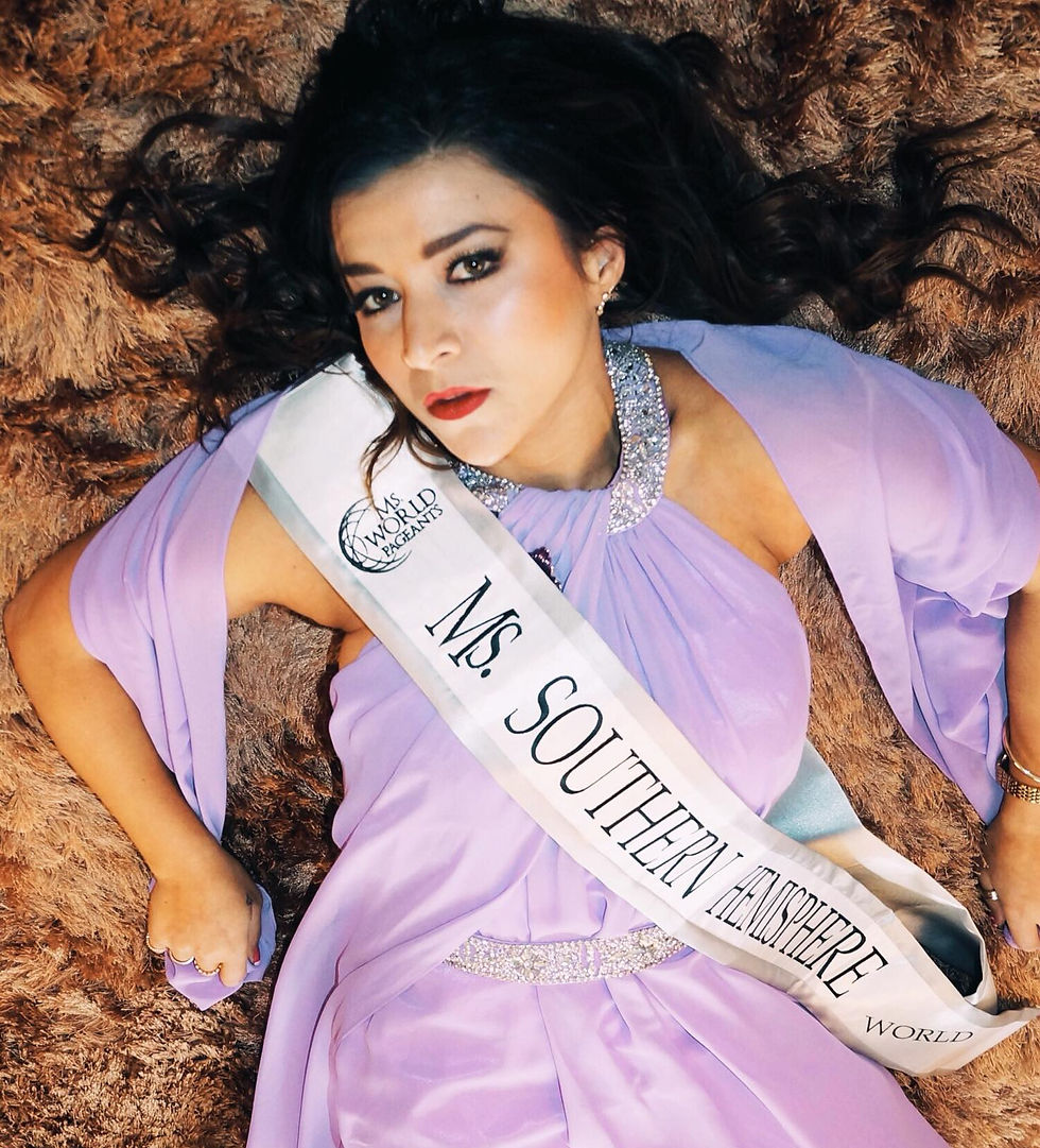 A person poses with a man in a superhero costume labeled "World Kindness Australia." A banner and table with plates are in the background.