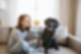 Teenage girl sitting on sofa playing with her black dog