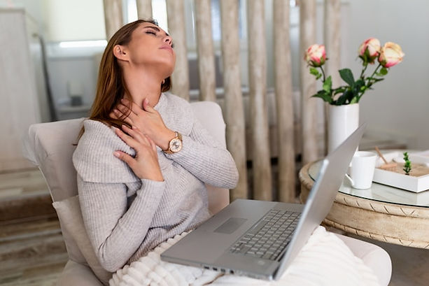 The image shows a woman sitting in a cozy indoor setting with a laptop on her lap.