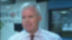 Man in checkered shirt and red tie smiles in a news office with WIBW-TV logos and "65 Years of Excellence" text on the wall.