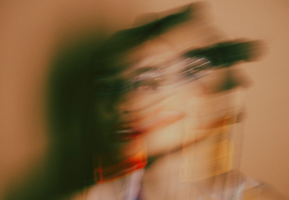 Blurred image of a face with motion effect, set against a beige background. Vibrant red and orange shades suggest movement and motion.