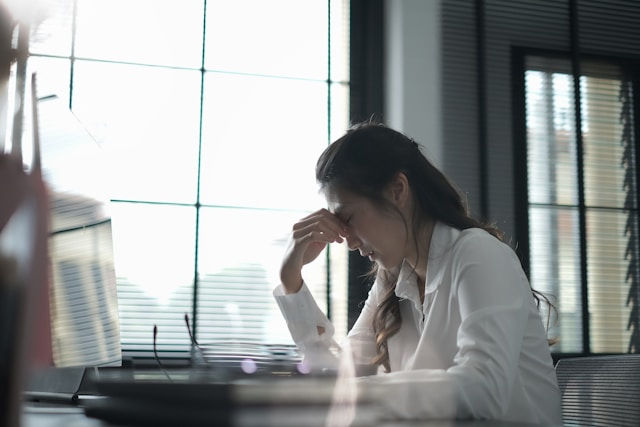 a woman pinching her nose in front of a computer