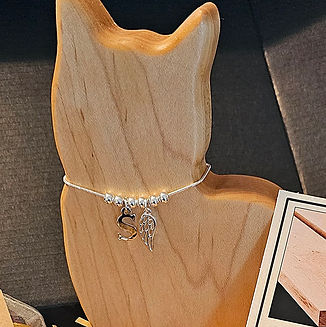 Shows a beautiful wooden cat figure with a silver necklace. The necklace has memorial charms. .