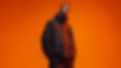 Fashion photography of GRID//NOIR luxury techwear model on orange background