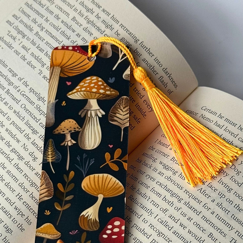 Black bookmark with yellow mushroom design and a yellow tassel laying on an open book.