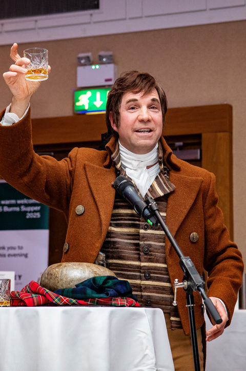 Actor portraying Robert Burns, photographed presenting the haggis at a Burns Night event.