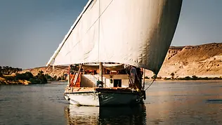 Dahabeya naviguant sur le Nil entre les rives de Haute-Égypte