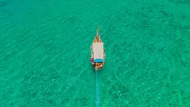 Dhow vu du ciel pendant un safari bleu à Zanzibar sur une mer turquoise au large des îlots.