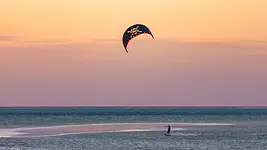 Kitesurfeur sur le lagon de Jambiani à Zanzibar au coucher du soleil, entre banc de sable et eaux peu profondes.