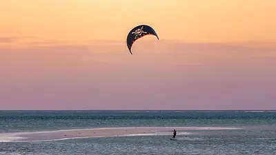 Kitesurfeur sur le lagon de Jambiani à Zanzibar au coucher du soleil, entre banc de sable et eaux peu profondes.