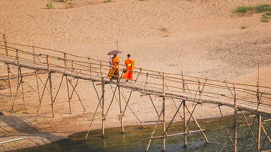 Moines bouddhistes traversant un pont près du Mékong à Luang Prabang au Laos