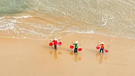 Femmes portant des paniers sur une plage du Centre Vietnam près de Hoi An