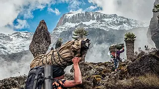 Porteurs en ascension sur les pentes rocheuses du Kilimandjaro en haute altitude