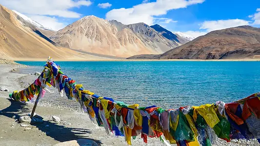 Lac Pangong bordé de drapeaux de prière et de montagnes minérales, au Ladakh.