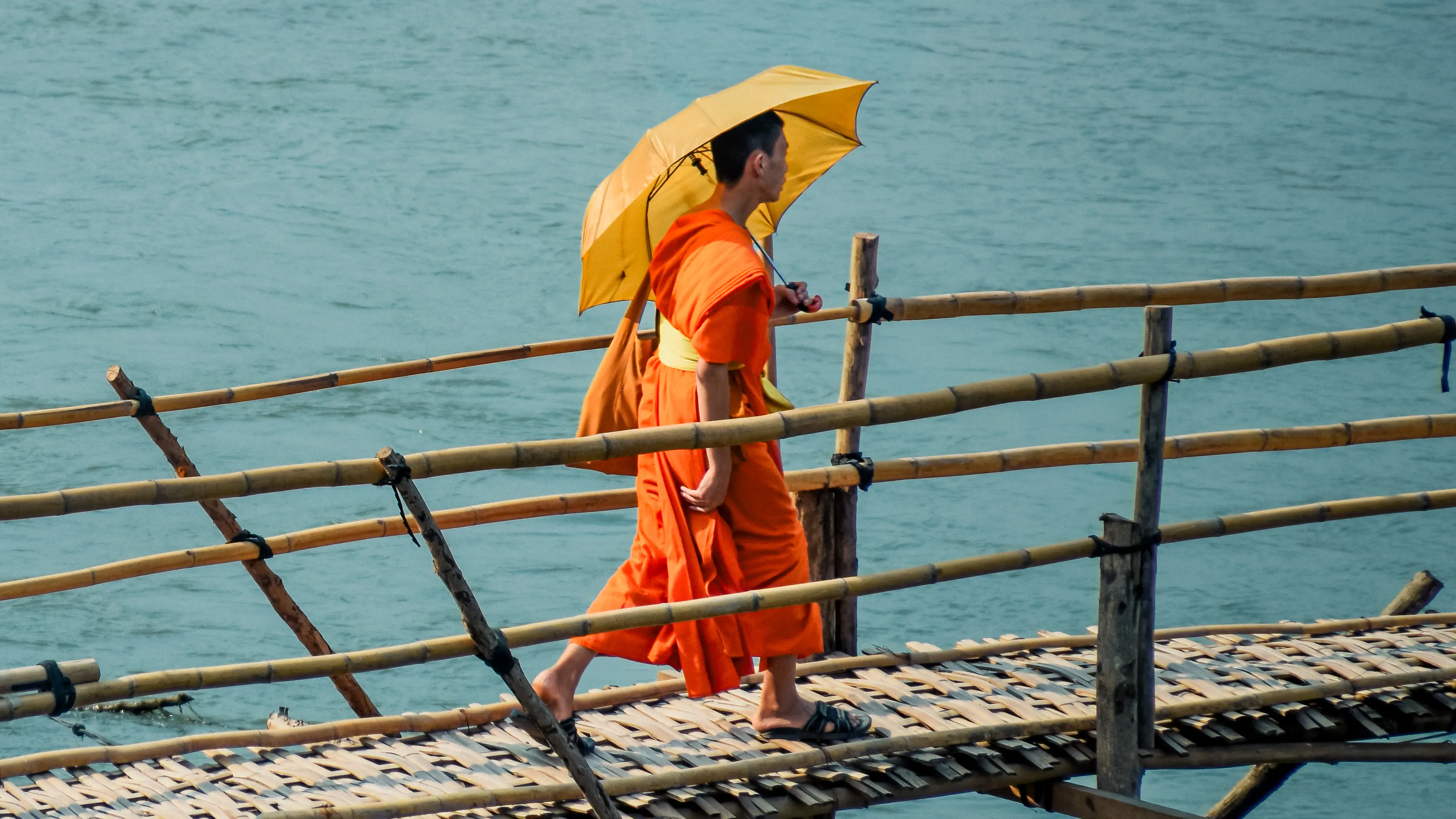 Moine marchant sur un pont au-dessus du Mékong à Luang Prabang