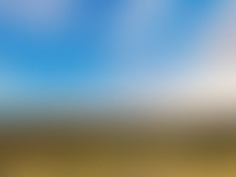 Rolling green hills under a bright blue sky with scattered clouds at sunset. Lush vegetation covers the landscape, creating a serene scene.