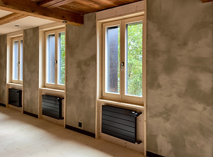 Ökologischer Lehmtrockenbau: Wand mit Strukturputz und eleganter Fensterverkleidung, die den Heizkörper ästhetisch in den Raum einbindet.