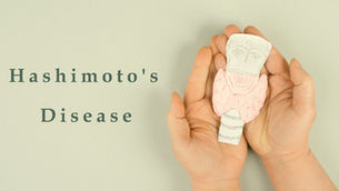 Hand holding a paper cut out of thyroid. Text saying "Hashimoto's Disease"