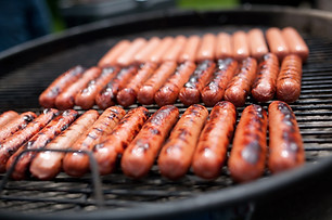 Several cooking hot dogs on a grill.jpg