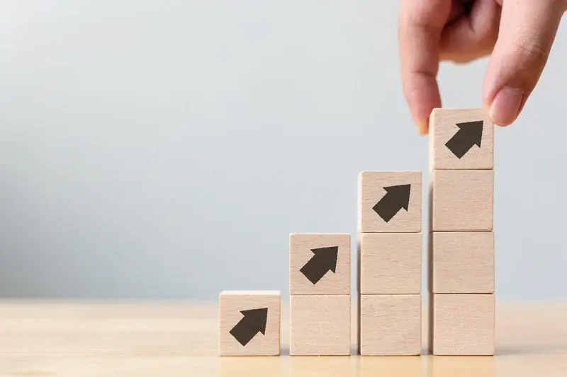 Wooden blocks increasing in stack size with arrows progressing upwards