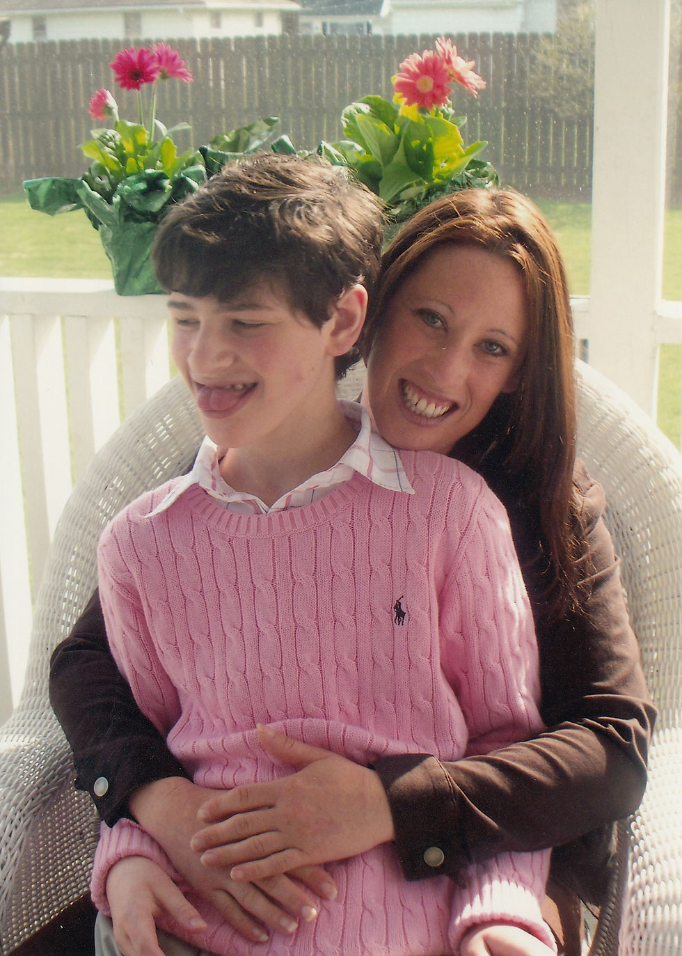 Cari and her son Logan, who has Angelman syndrome, smiling together on a porch.